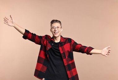 Photo of Happy man welcoming friends or guests with wide open arms on beige background