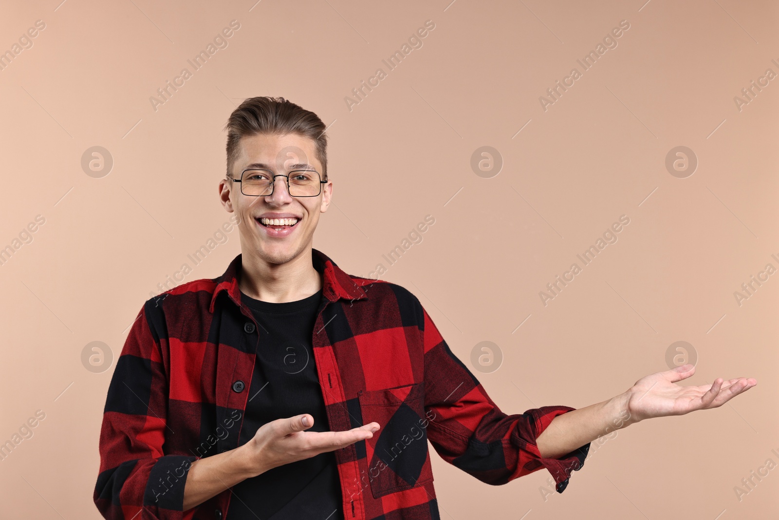 Photo of Happy man welcoming friends or guests on beige background