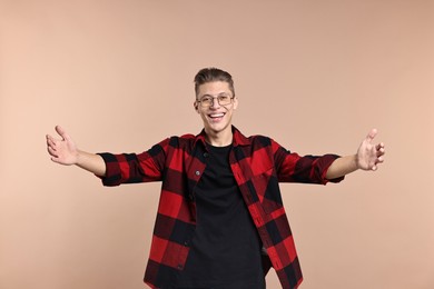 Photo of Happy man welcoming friends or guests with wide open arms on beige background