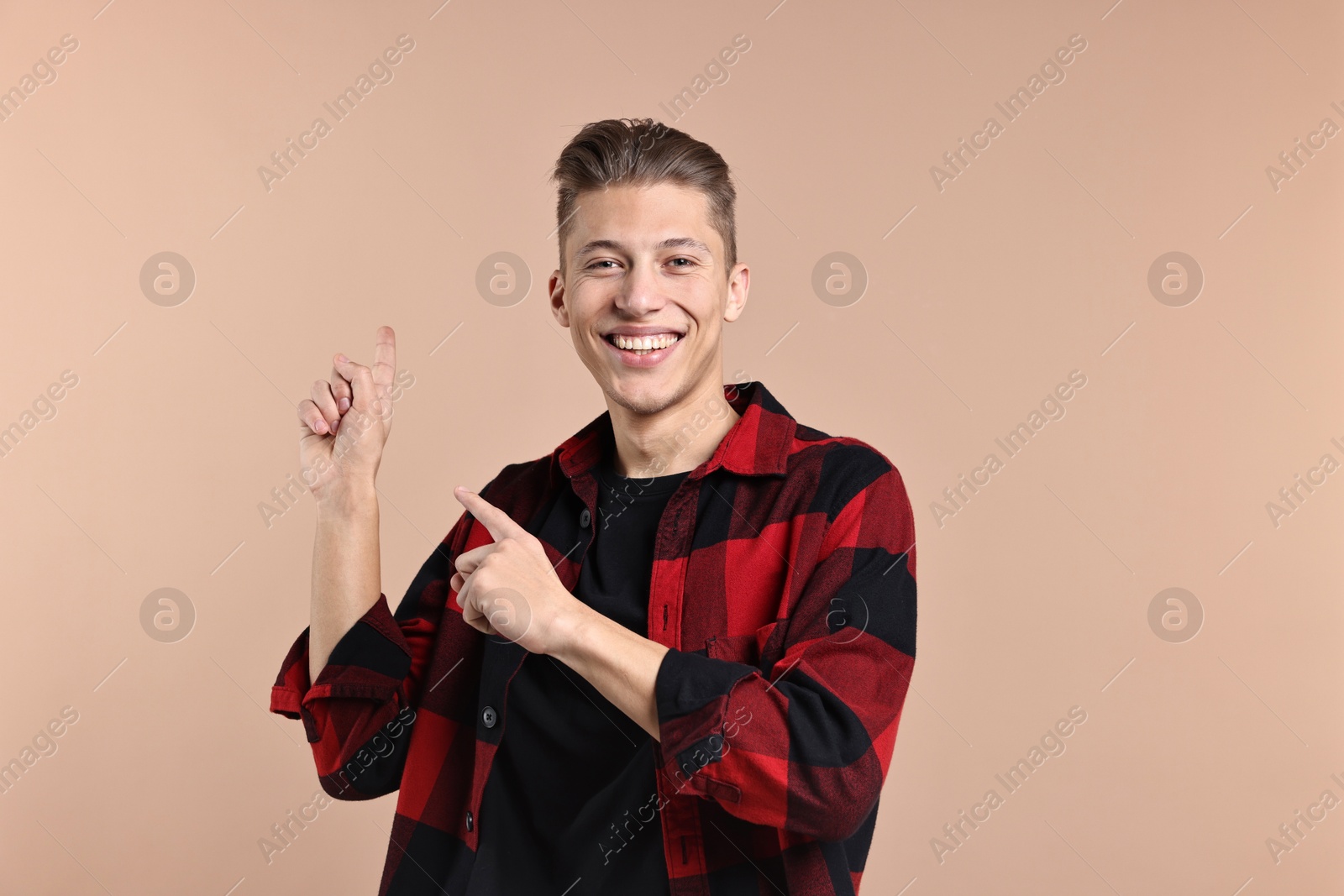 Photo of Happy man welcoming friends or guests on beige background