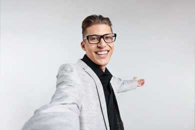 Photo of Happy businessman welcoming clients or partners on grey background, view through front camera of gadget