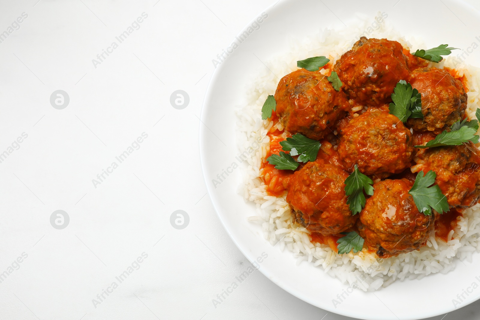 Photo of Delicious meatballs with rice, sauce and parsley on white table, top view. Space for text