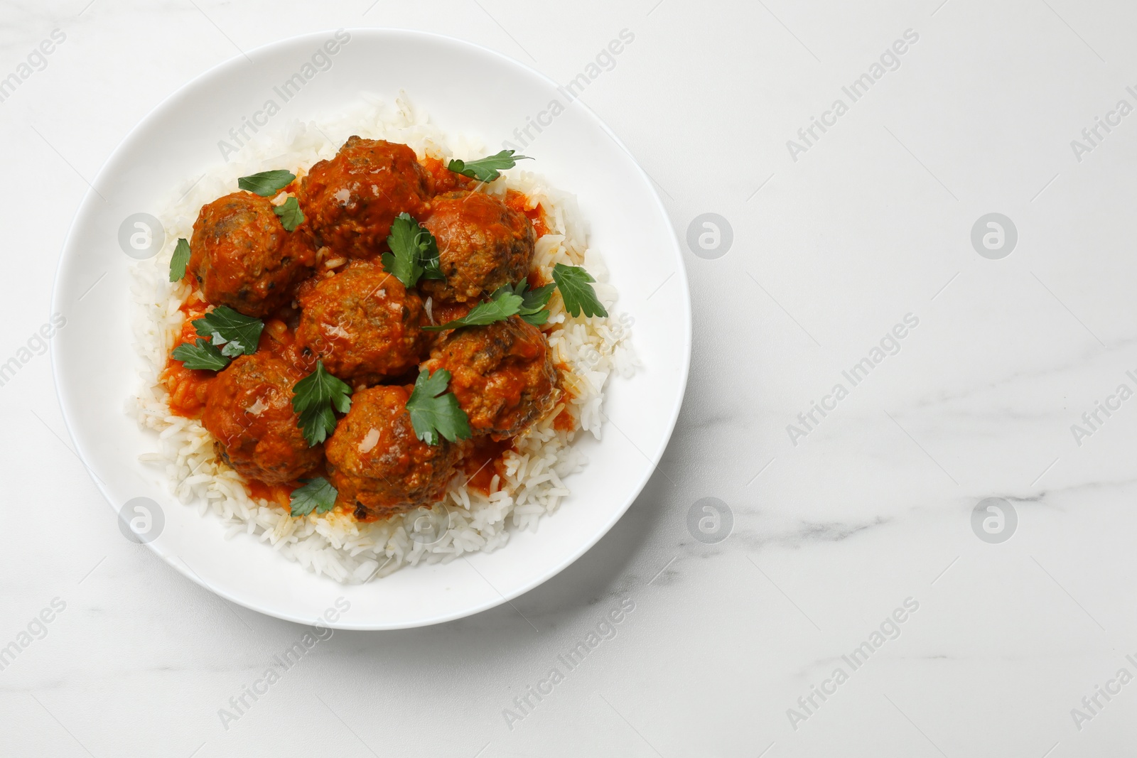 Photo of Delicious meatballs with rice, sauce and parsley on white marble table, top view. Space for text