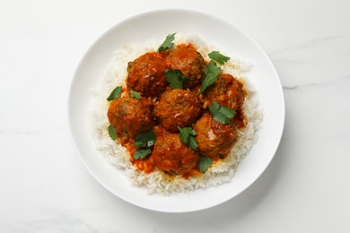 Photo of Delicious meatballs with rice, sauce and parsley on white marble table, top view