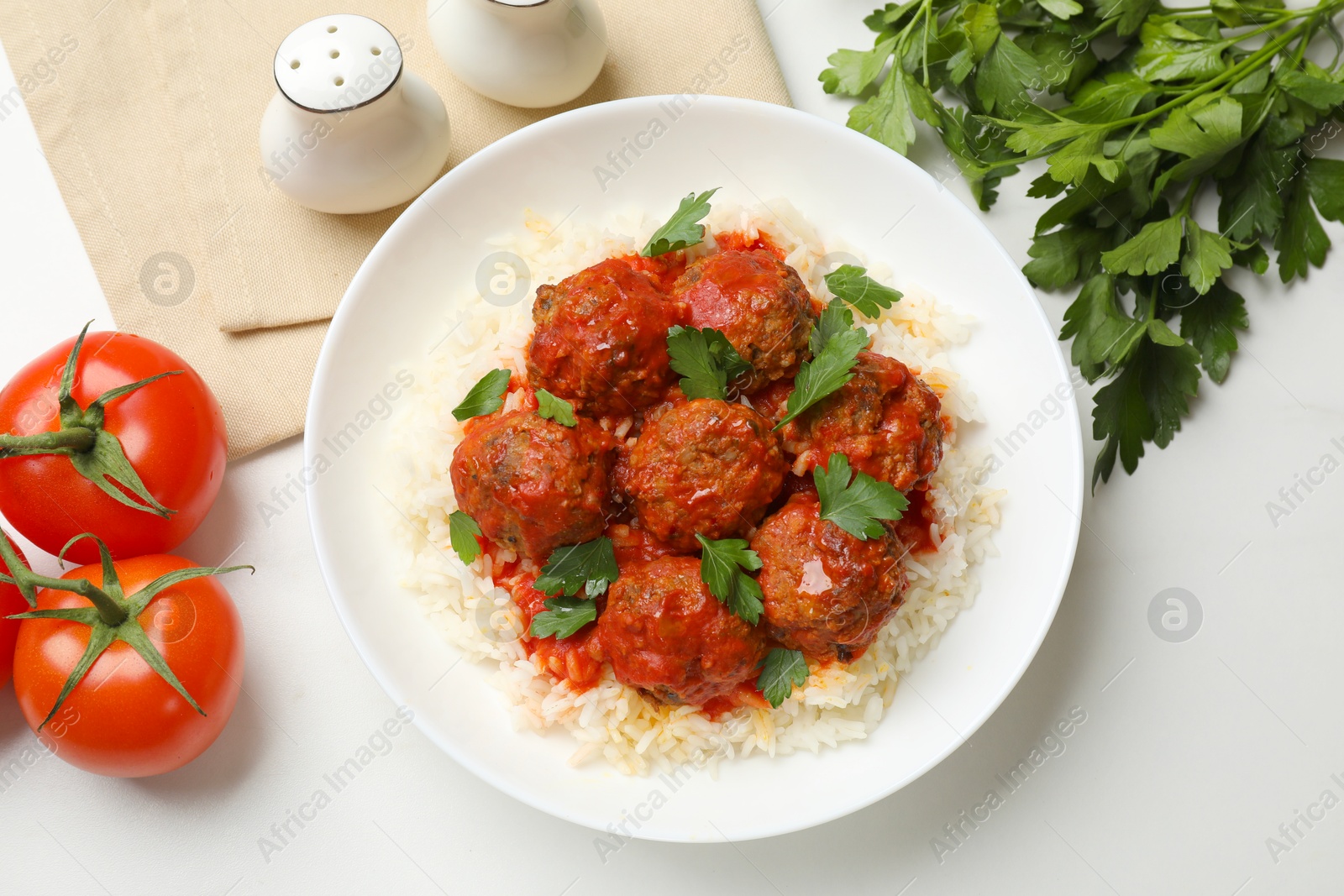 Photo of Delicious meatballs with rice, sauce and parsley on white table, flat lay