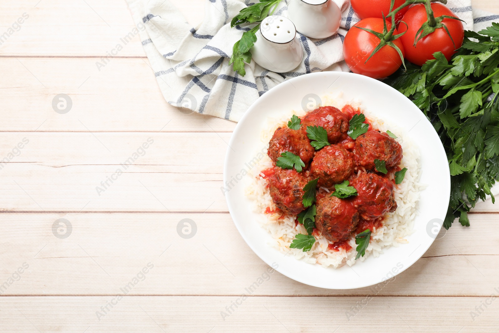 Photo of Delicious meatballs with rice, sauce and parsley on light wooden table, flat lay. Space for text