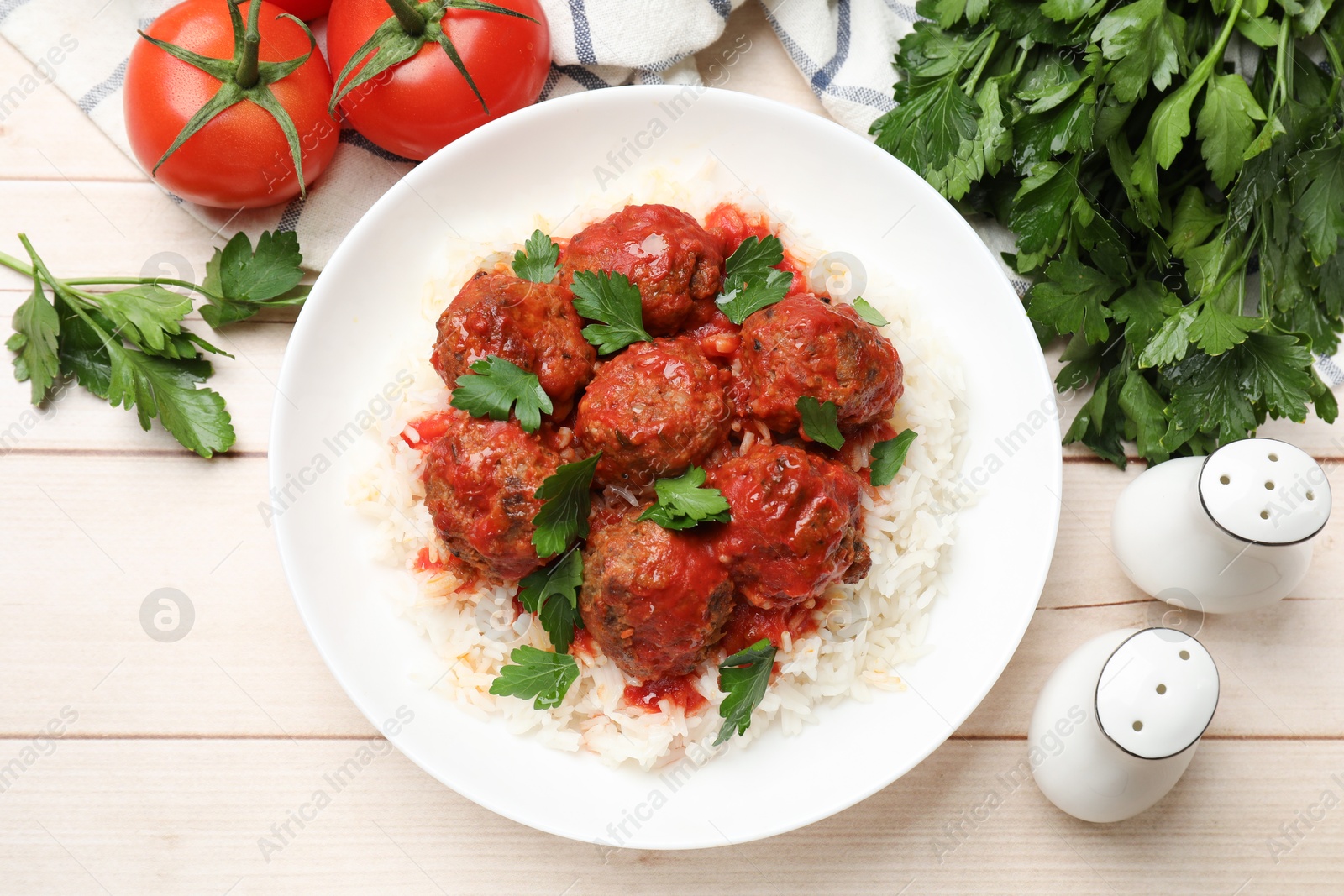 Photo of Delicious meatballs with rice, sauce and parsley on light wooden table, flat lay