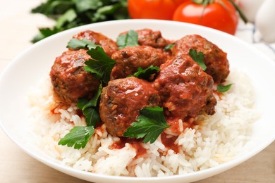 Photo of Delicious meatballs with rice, sauce and parsley on light wooden table, closeup