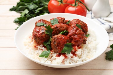 Photo of Delicious meatballs with rice, sauce and parsley on light wooden table, closeup