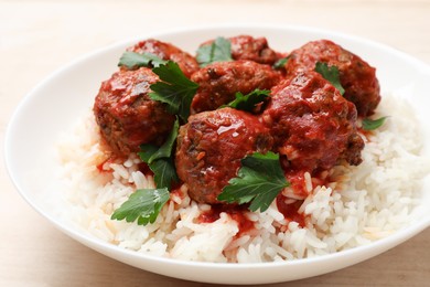 Photo of Delicious meatballs with rice, sauce and parsley on light wooden table, closeup