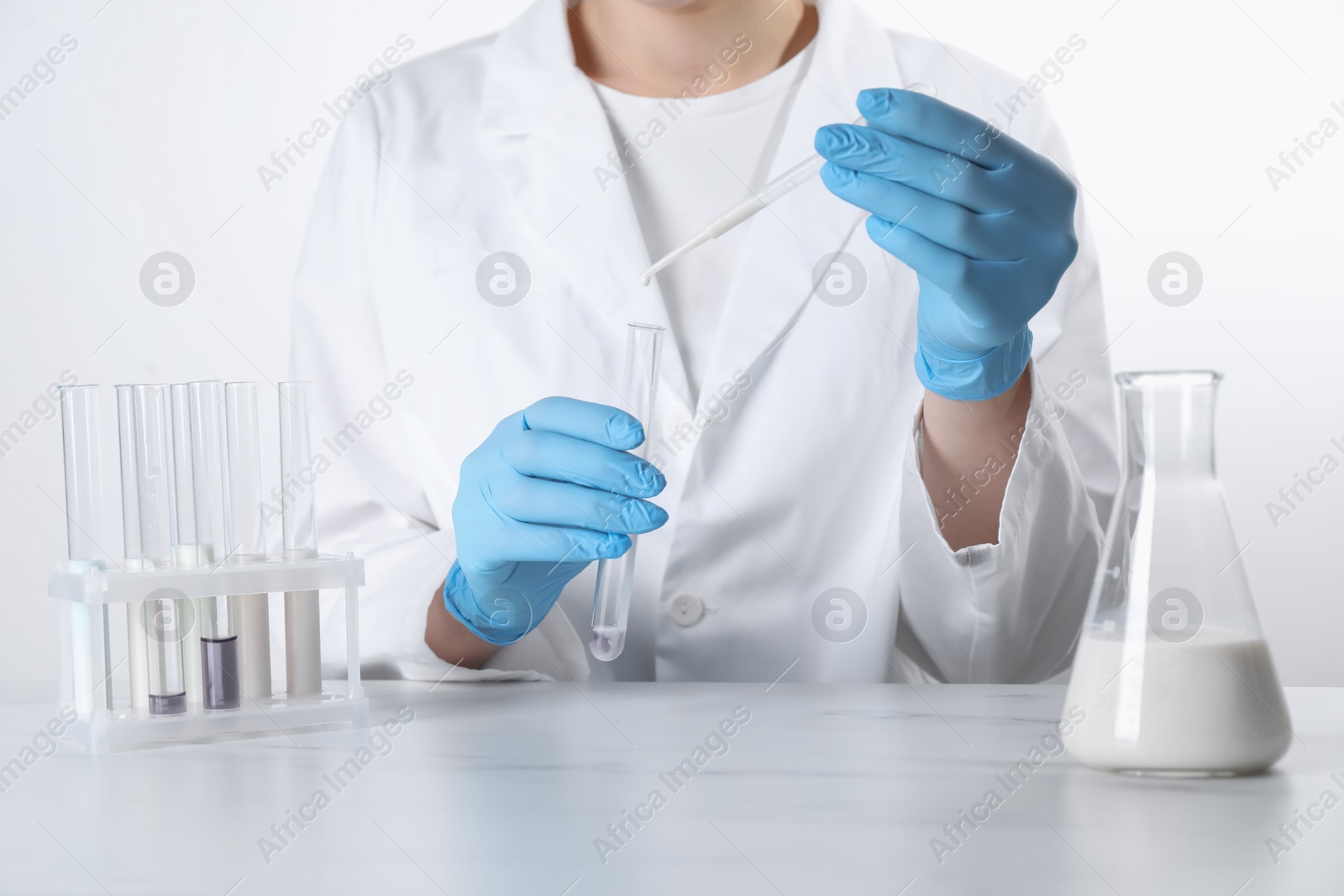 Photo of Laboratory testing. Scientist dripping liquid into test tube at table, closeup