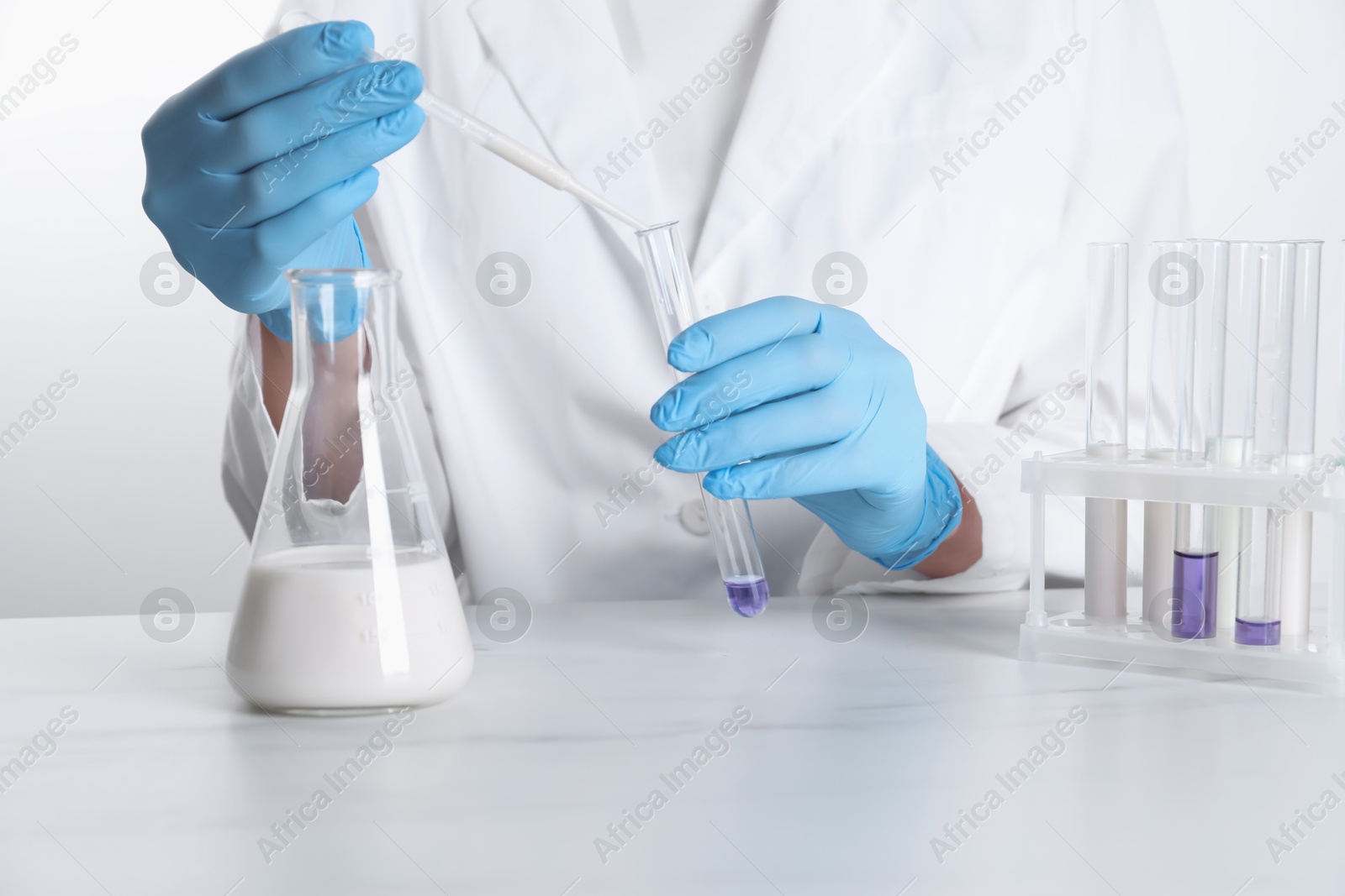 Photo of Laboratory testing. Scientist working with glassware at white marble table, closeup