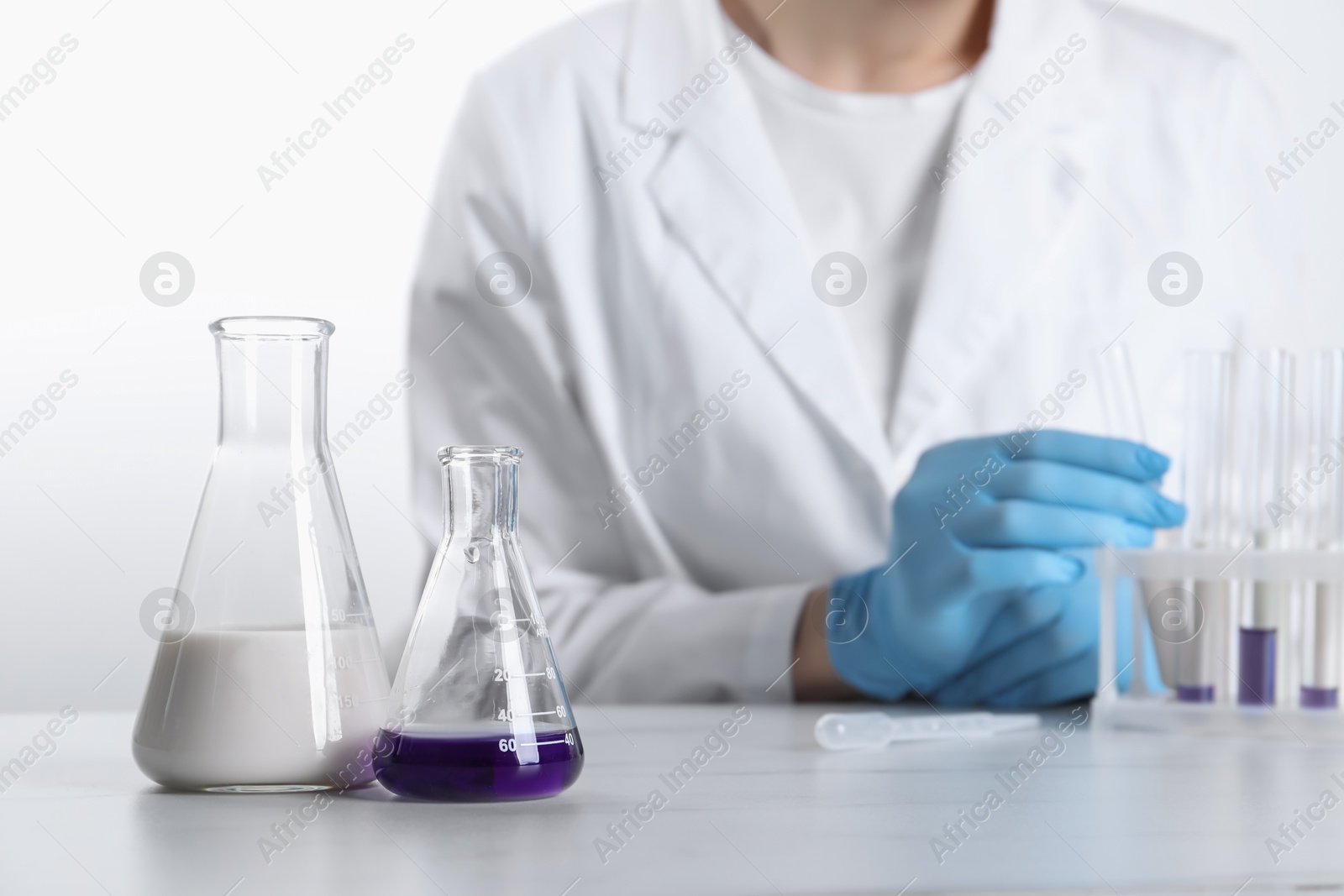 Photo of Laboratory testing. Scientist working with glassware at white marble table, closeup