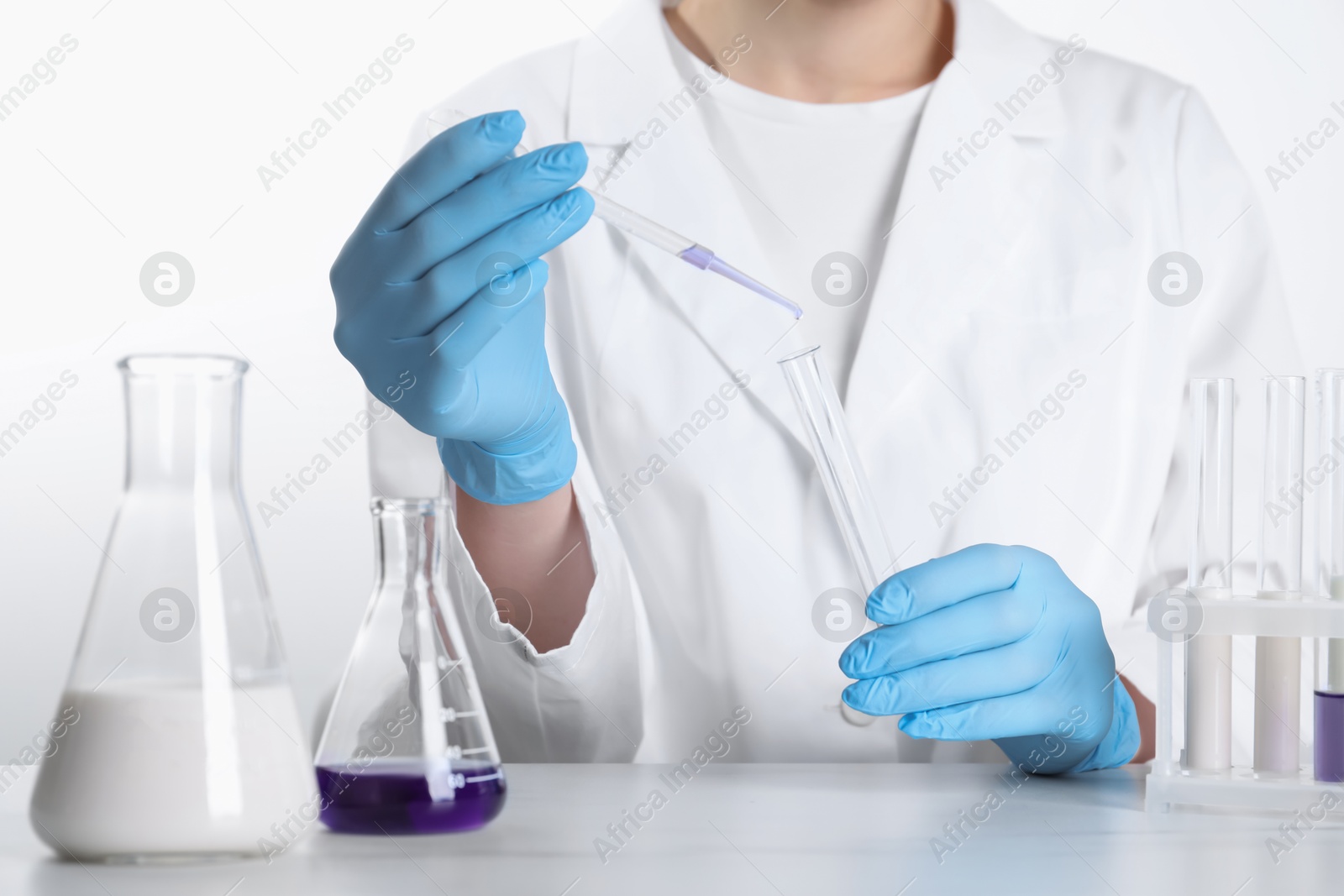 Photo of Laboratory testing. Scientist working with glassware at white marble table, closeup