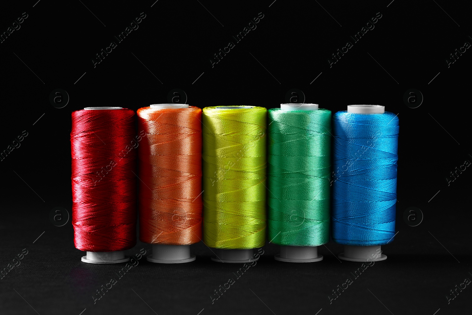 Photo of Spools of colorful sewing threads on black background