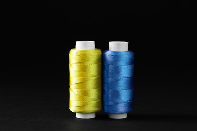 Photo of Spools of colorful sewing threads on black background