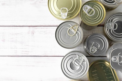 Photo of Many closed tin cans on white wooden table, flat lay. Space for text