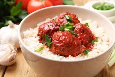 Photo of Tasty meatballs with sauce, rice and products on wooden table, closeup