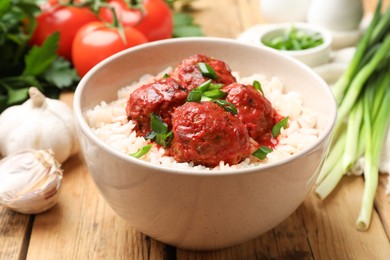 Photo of Tasty meatballs with sauce, rice and products on wooden table, closeup