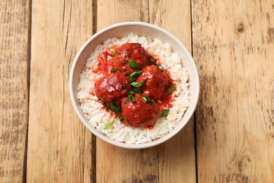 Photo of Tasty meatballs with sauce and rice on wooden table, top view