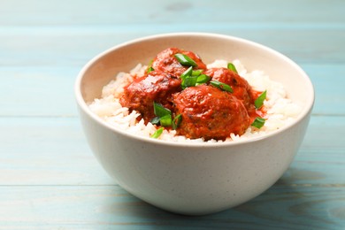 Photo of Tasty meatballs with sauce and rice on light blue wooden table, closeup