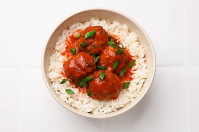 Photo of Tasty meatballs with sauce and rice on white tiled table, top view