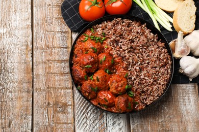 Photo of Tasty meatballs with sauce, brown rice and products on wooden table, flat lay