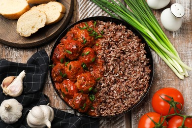 Photo of Tasty meatballs with sauce, brown rice and products on wooden table, flat lay