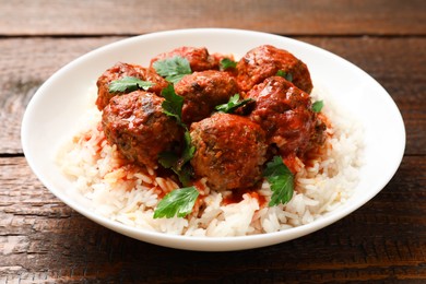 Photo of Tasty meatballs with sauce and rice on wooden table, closeup