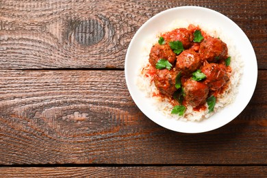 Photo of Tasty meatballs with sauce and rice on wooden table, top view. Space for text