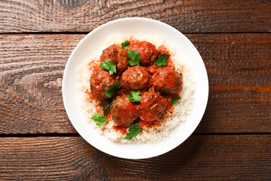 Photo of Tasty meatballs with sauce and rice on wooden table, top view