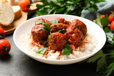 Photo of Tasty meatballs with sauce, rice and products on black table, closeup