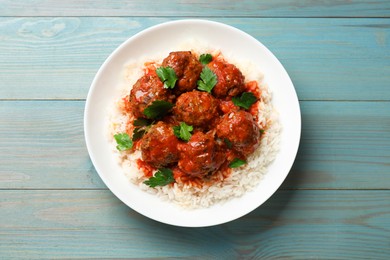 Photo of Tasty meatballs with sauce and rice on light blue wooden table, top view