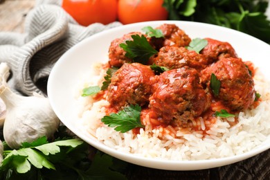 Photo of Tasty meatballs with sauce, rice and products on wooden table, closeup