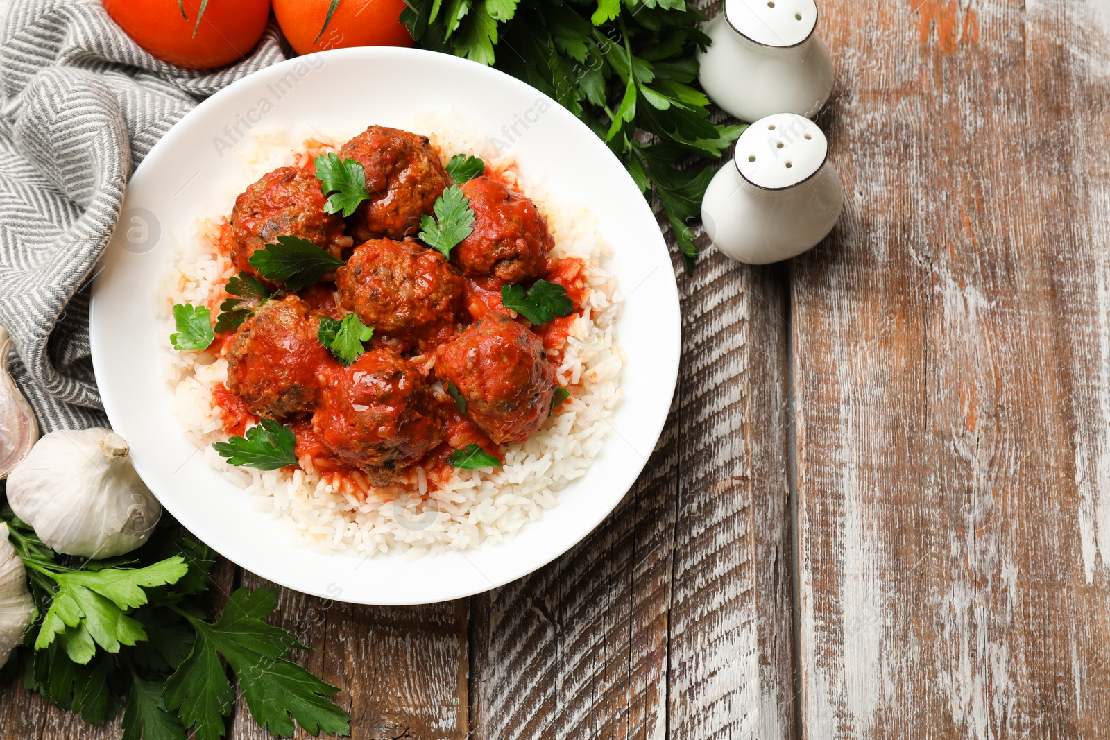 Photo of Tasty meatballs with sauce, rice and products on wooden table, flat lay. Space for text