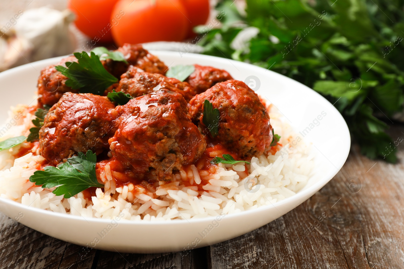 Photo of Tasty meatballs with sauce, rice and products on wooden table, closeup