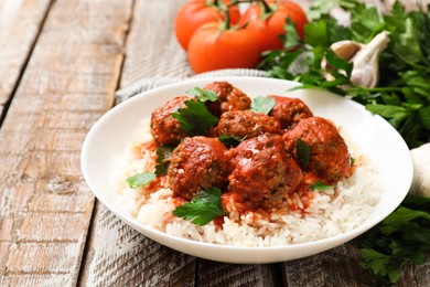 Photo of Tasty meatballs with sauce, rice and products on wooden table, closeup