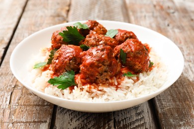 Photo of Tasty meatballs with sauce and rice on wooden table, closeup