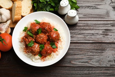 Photo of Tasty meatballs with sauce, rice and products on wooden table, flat lay. Space for text