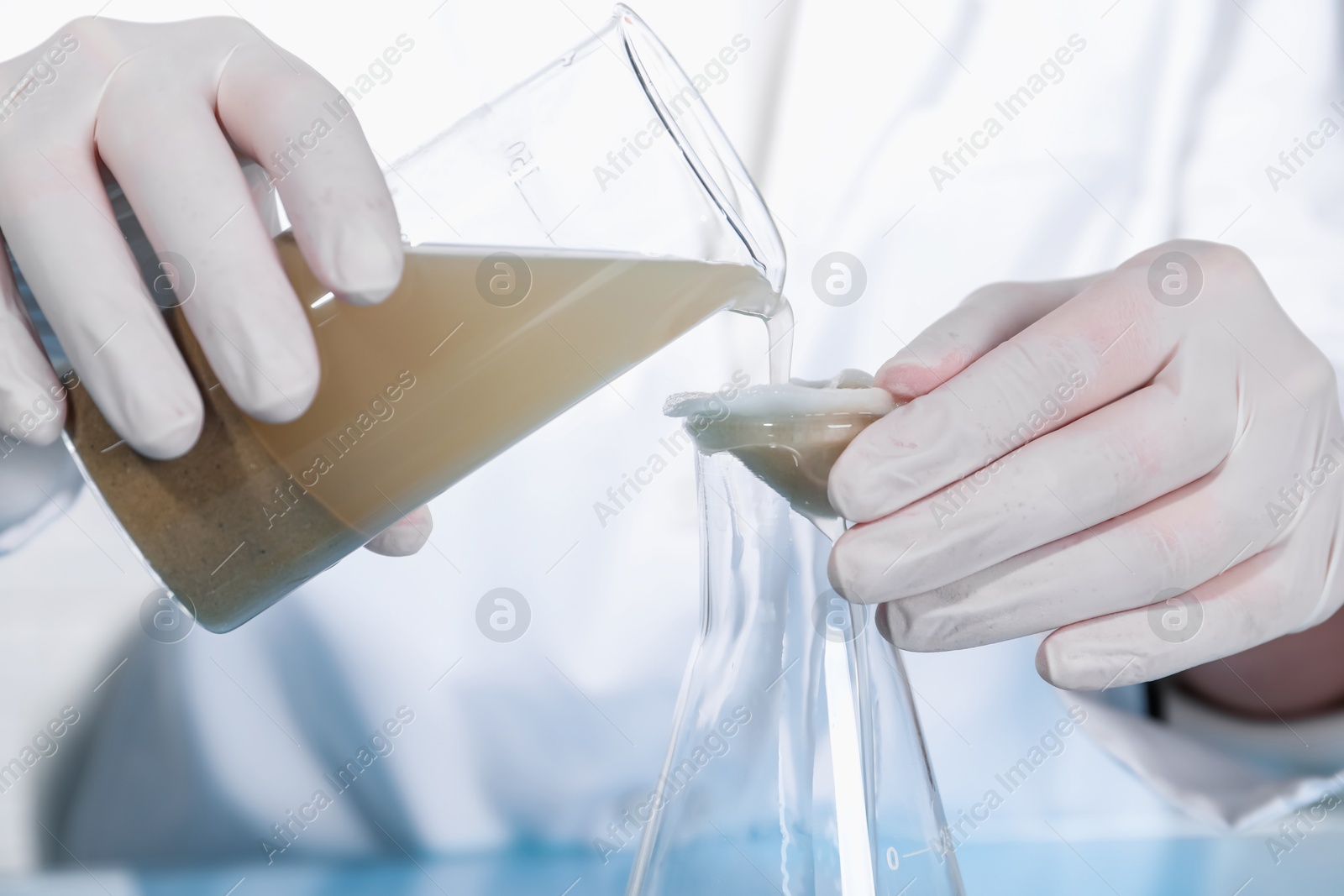 Photo of Laboratory testing. Scientist filtering soil sample, closeup