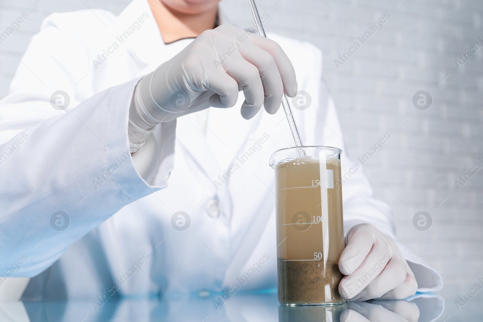 Photo of Laboratory testing. Scientist preparing soil extract at table indoors, closeup