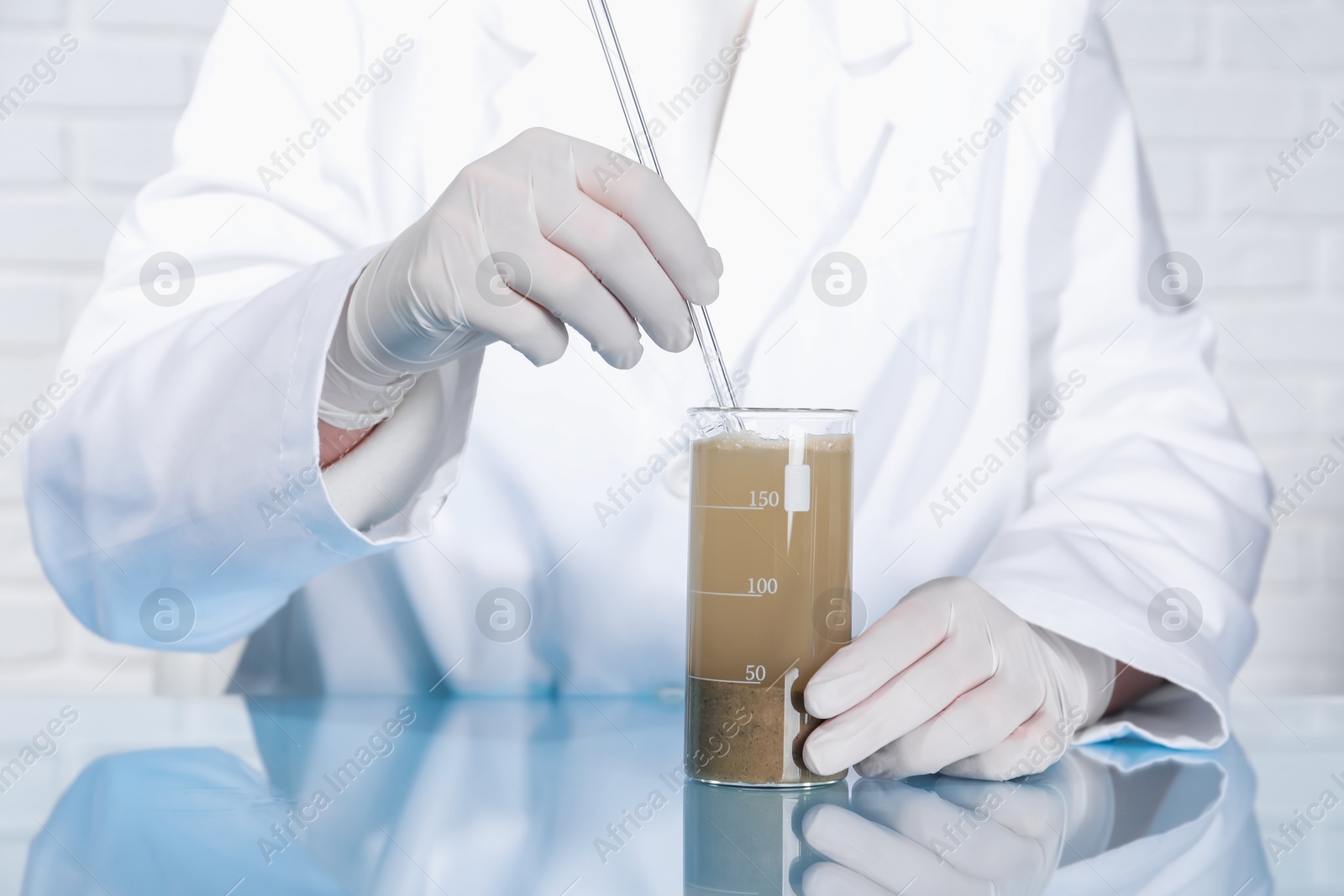 Photo of Laboratory testing. Scientist preparing soil extract at table indoors, closeup