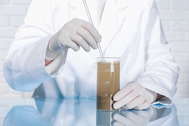 Photo of Laboratory testing. Scientist preparing soil extract at table indoors, closeup