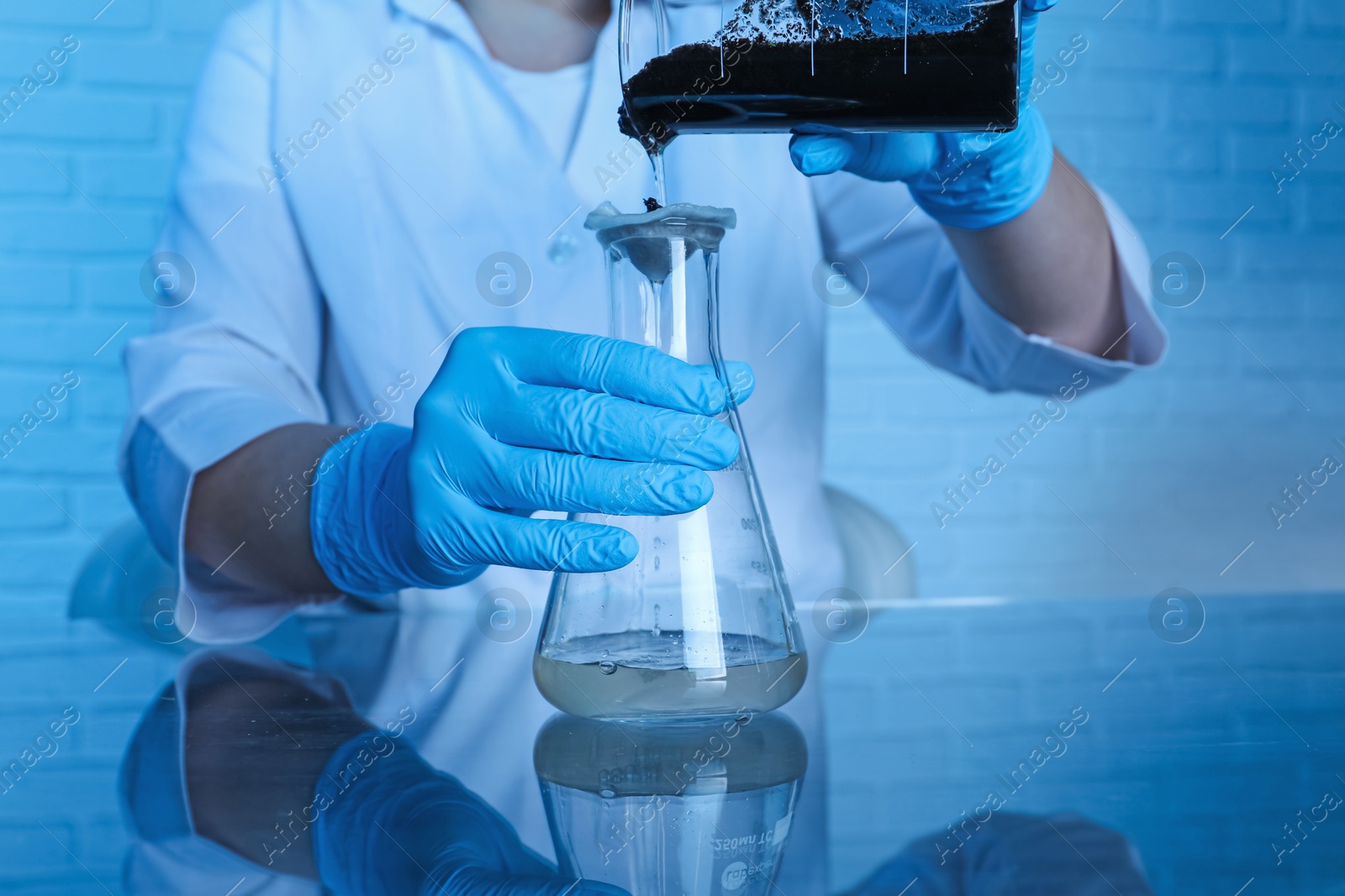 Photo of Laboratory testing. Scientist filtering soil sample at table indoors, closeup