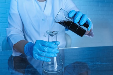 Photo of Laboratory testing. Scientist filtering soil sample at table indoors, closeup