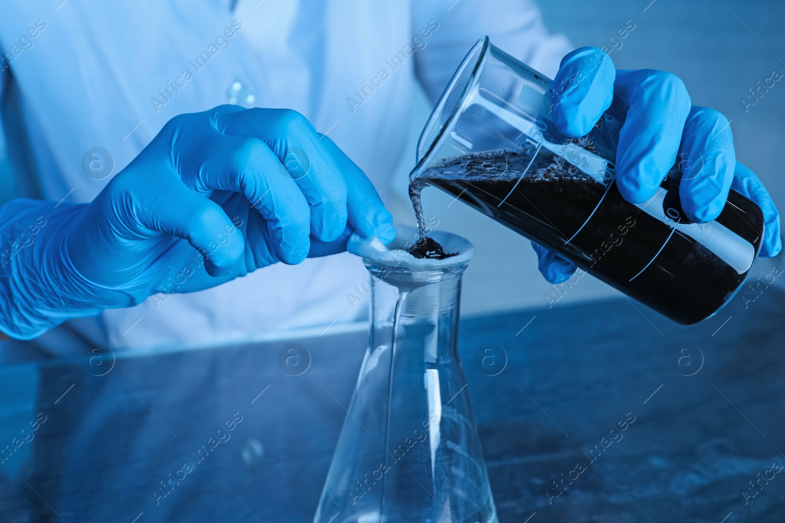 Photo of Laboratory testing. Scientist filtering soil sample at table indoors, closeup