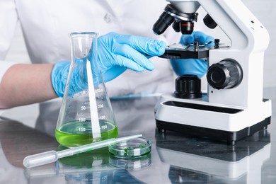 Photo of Laboratory testing. Scientist examining sample under microscope at table indoors, closeup