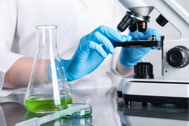 Photo of Laboratory testing. Scientist examining sample under microscope indoors, closeup