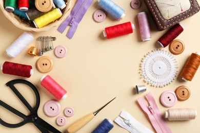 Photo of Frame of different sewing supplies on beige background, flat lay. Space for text