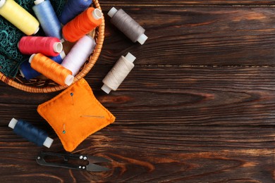 Photo of Different sewing supplies on wooden background, flat lay. Space for text